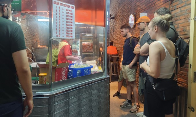 Du khách nước ngoài xếp hàng mua bánh mì tại một tiệm ở quận 1. Ảnh: Bích Phương